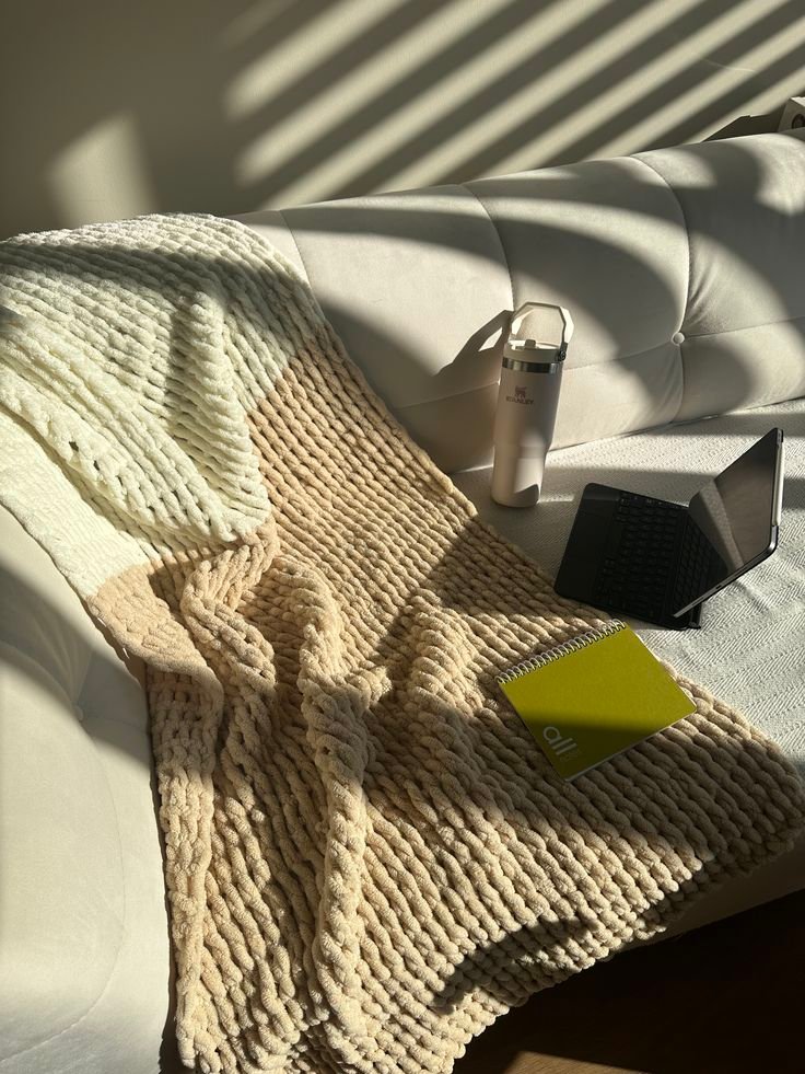 knitblank “Chunky knit blanket draped over a reading chair — cozy fall reading nook”